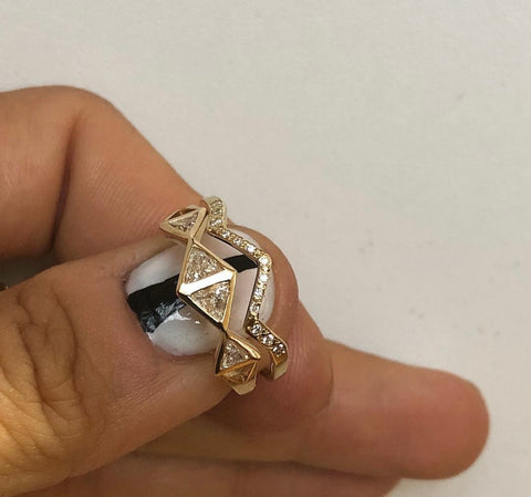 Gold ring with geometric design on a finger against a white background with the nester band