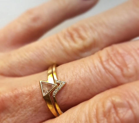 A 10kt yellow gold ring with a step cut diamond shown on a finger with a nester band
